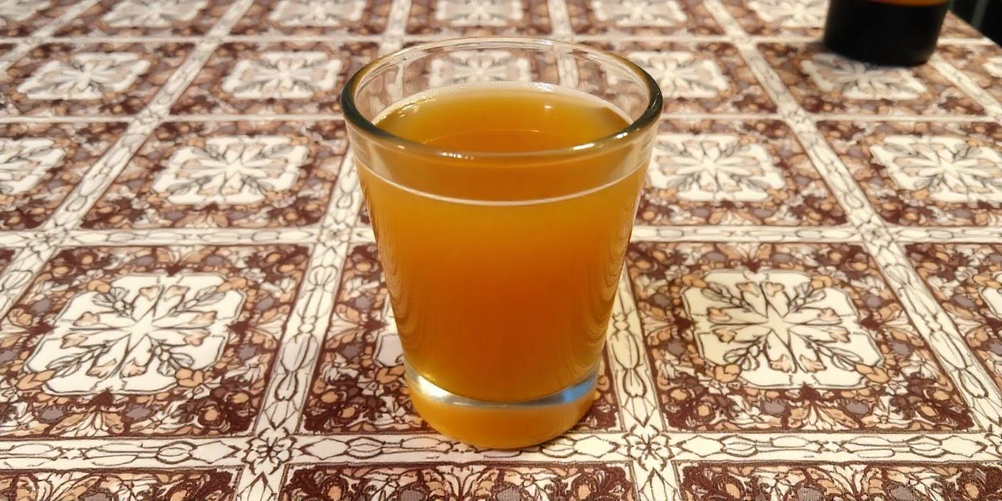 A glass of fermented drink placed on a patterned tablecloth.