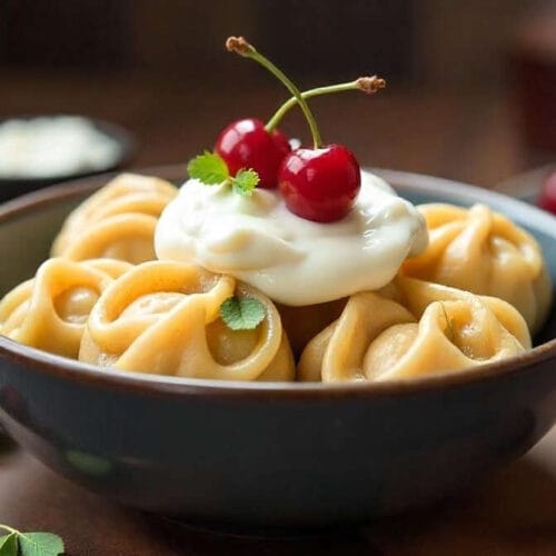 Sweet Dumplings with Sour Cream and Cherries – A dessert dumpling dish topped with sour cream and cherries.