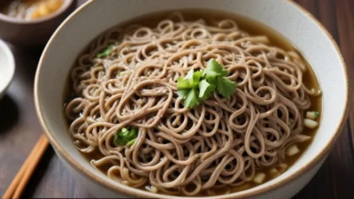 A bowl of traditional Japanese soba noodles served with dipping sauce and garnished with green onions and seaweed.