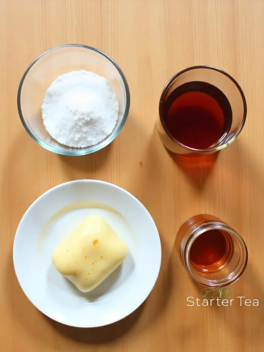 Kombucha ingredients including tea, sugar, SCOBY, and starter liquid on a wooden table.