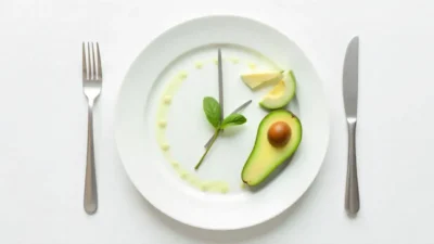 A plate styled as a clock with utensils as hands and healthy food placed in a limited time window, representing intermittent fasting.