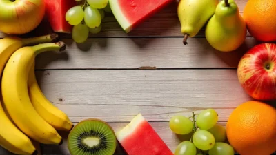 Assorted budget-friendly fruits under $1, including bananas, apples, pears, grapes, oranges, kiwi, watermelon, and cantaloupe, displayed on a rustic table.