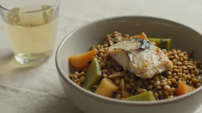 A warm, soft-textured balanced meal with vegetables and protein beside a glass of water, symbolizing gentle nutrition for older adults.
