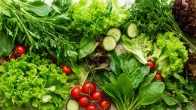 Fresh mixed salad greens with vegetables on a light background
