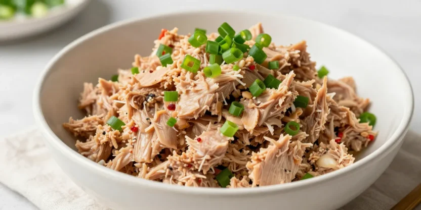 Spicy tuna salad in a bowl with green onions, shot in natural light